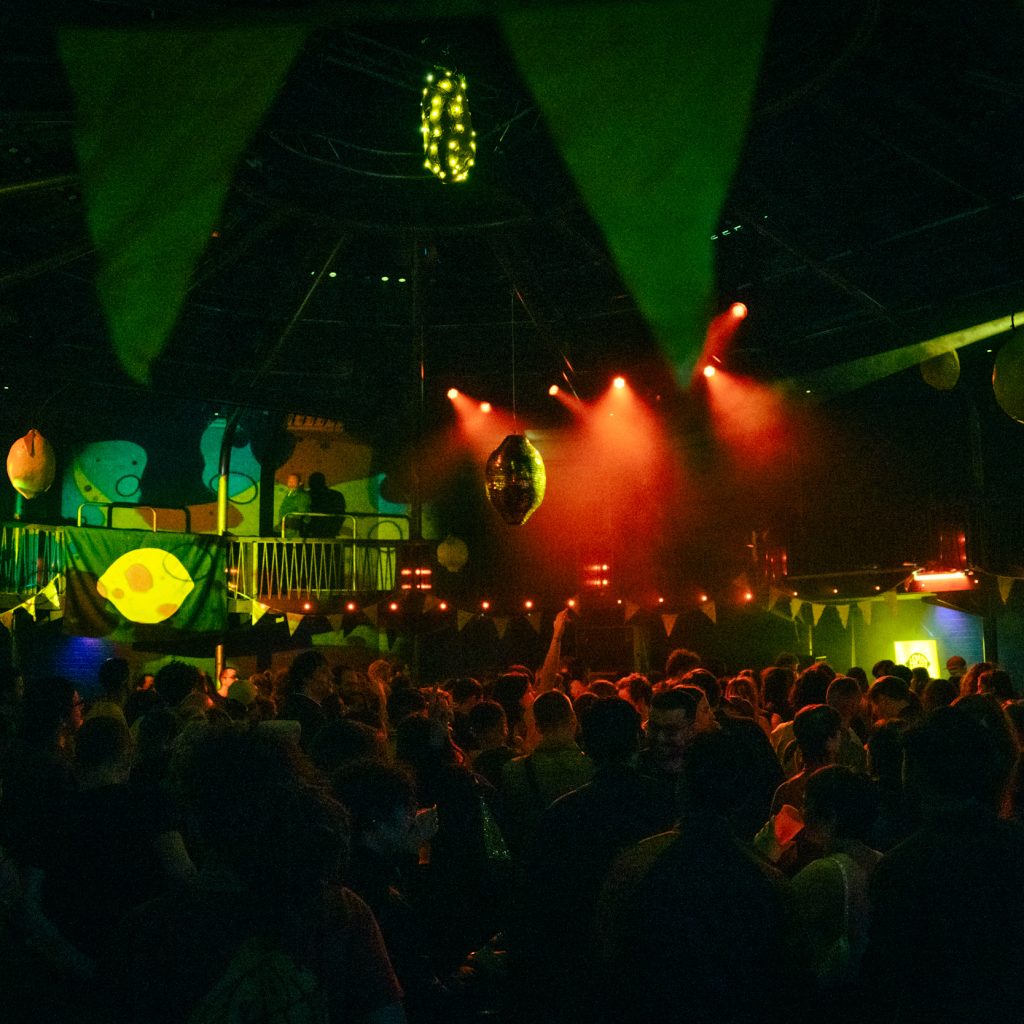 Crowds of people dancing with yellow and red strobe lighting in a dark room